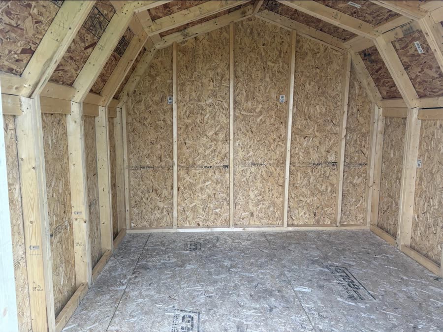 Inside an empty Apex barn shed, with OSB walls and a wood floor