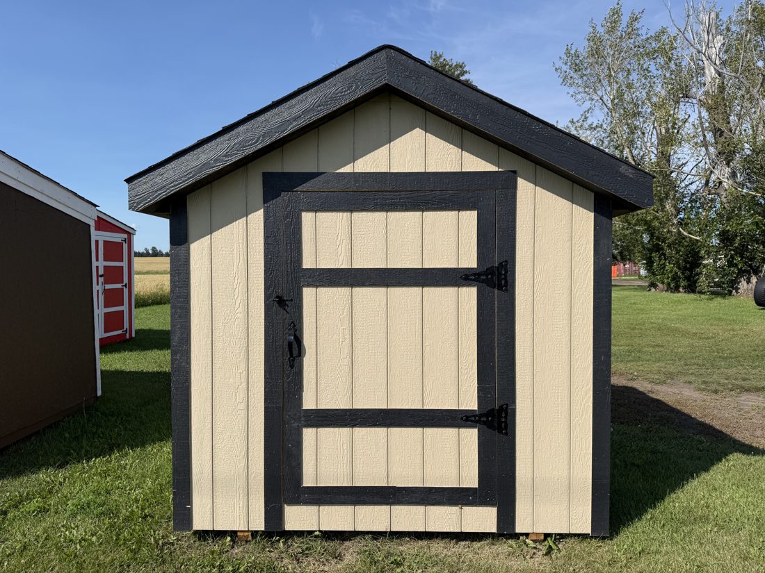 A tan Apex gable shed with black trim in a field