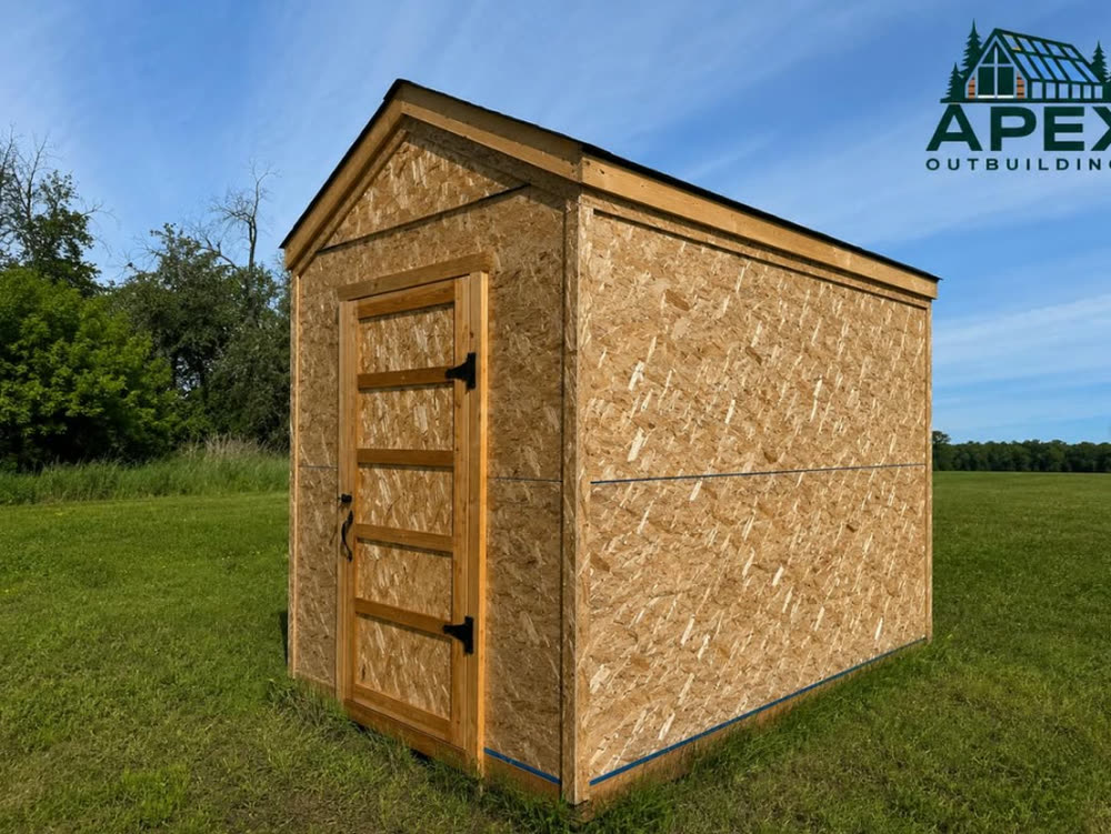 An Apex shed in bare OSB standing in a field